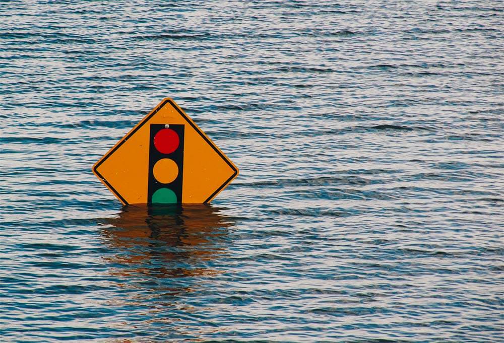 A stop light sign almost covered by flooding